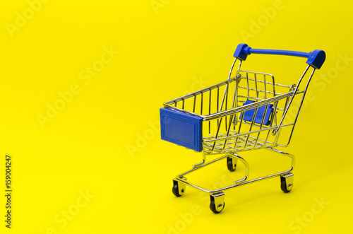 mini supermarket shopping cart on yellow background, holiday sale and shopping concept, selective focus, copy space