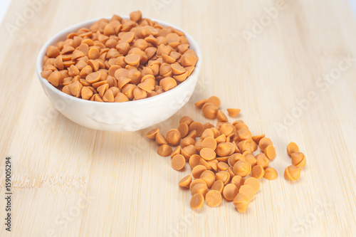 Butterscotch chips in white bowl on wooden background