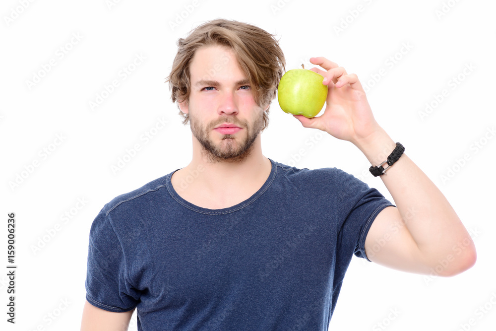 Man in blue tshirt looking attentively and holding green apple Man in blue tshirt looking attentively and holding green apple