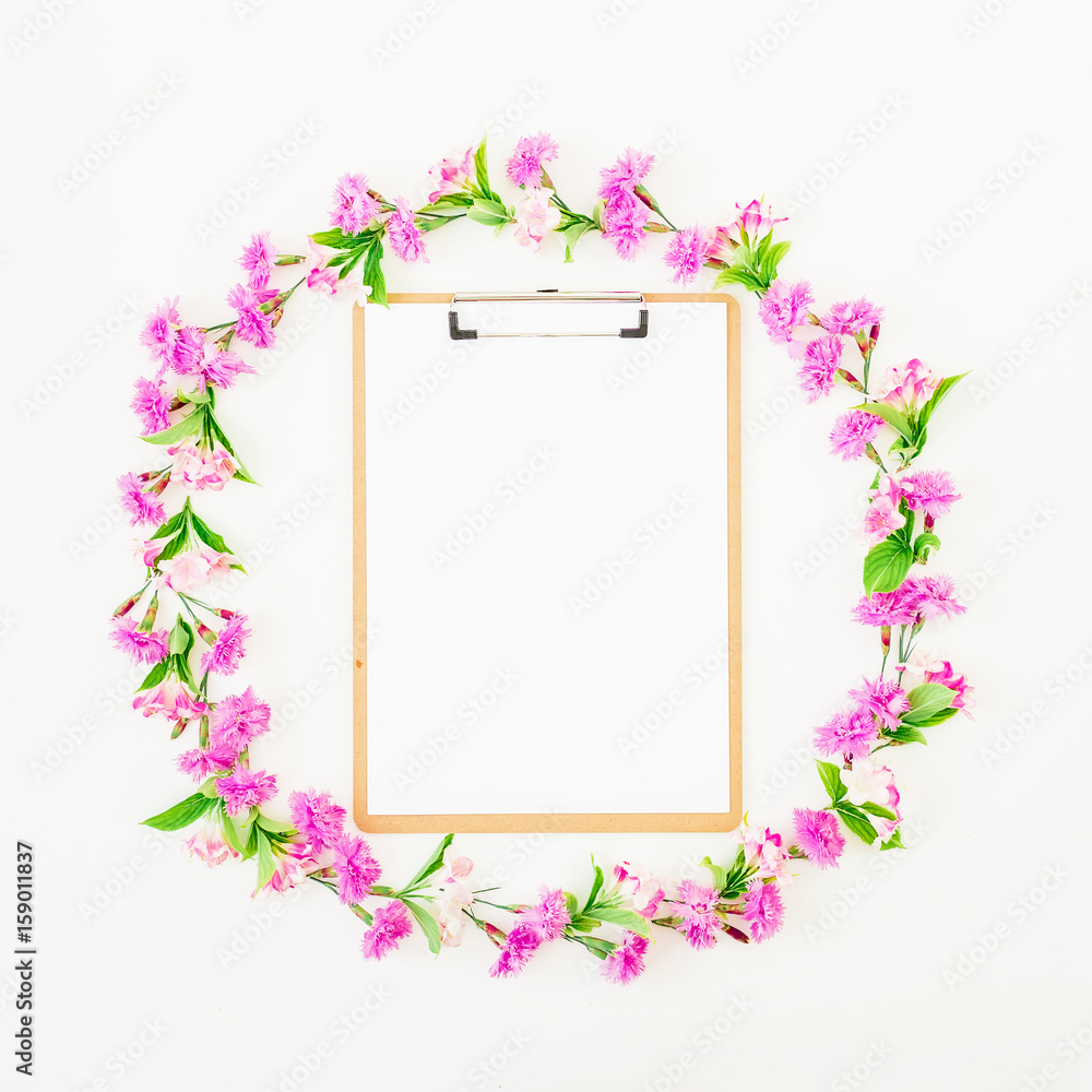Round frame made of flowers and clipboard on white background. Flat lay, top view. Blogger or freelancer composition Round frame made of flowers and clipboard on white background. Flat lay, top view. Blogger or freelancer composition