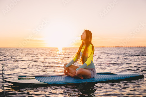 Stand up paddle boarding on a quiet sea with warm sunset colors. Relaxing on ocean © artifirsov