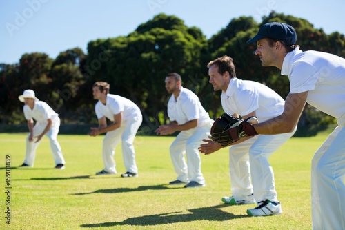 Side view of players bending while standing at grassy field