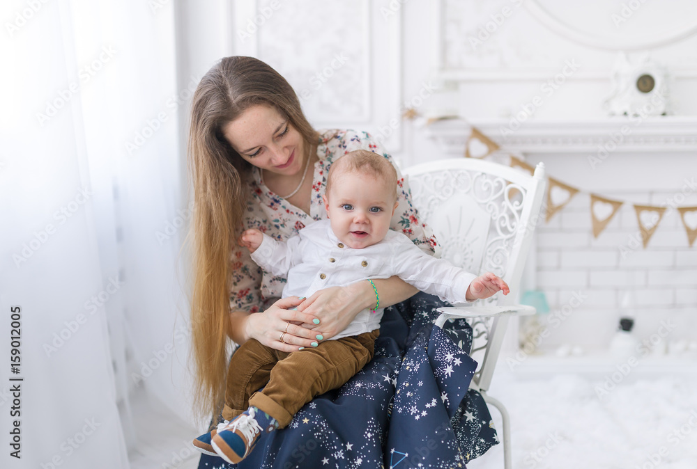 Portrait of laughing young mum together with a small son in a white room interior Portrait of laughing young mum together with a small son in a white room interior