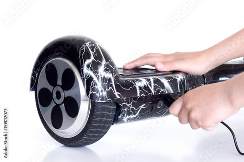 The boy's hands connect the gyro scooter hoverboard battery charger. photo