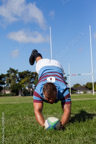 Full length of player playing rugby against blue sky