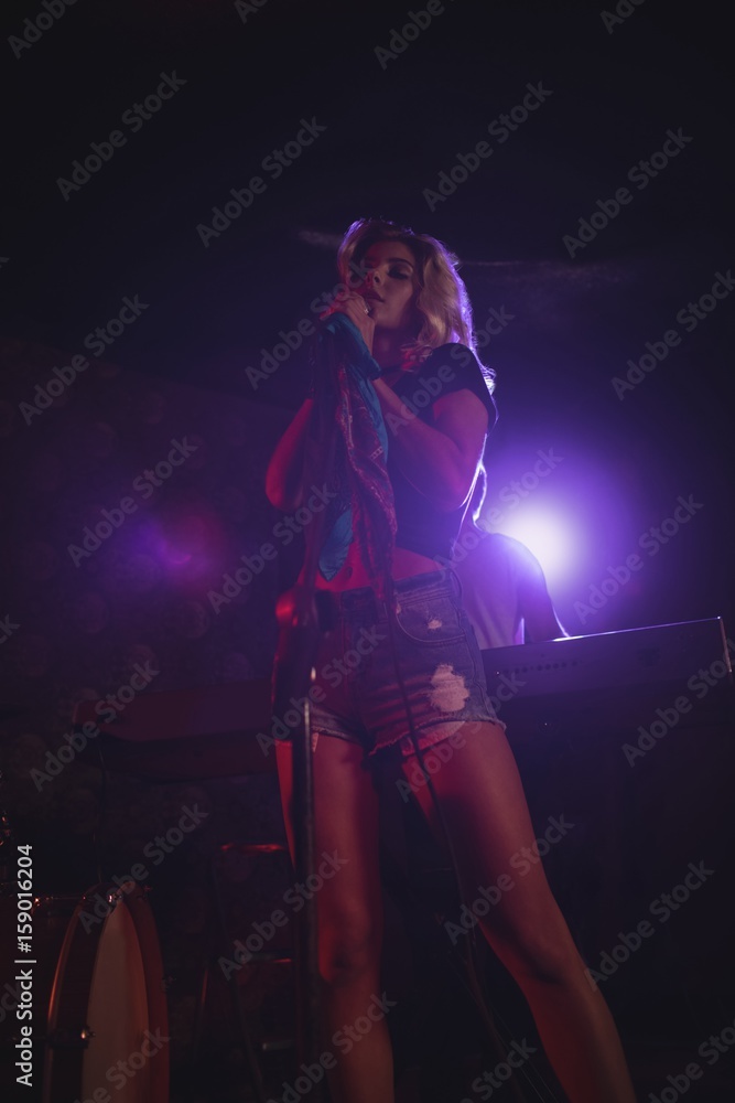 Female singer standing on illuminated stage in nightclub