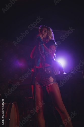 Female singer standing on illuminated stage in nightclub