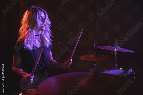 Foto Confident female drummer performing on illuminated stage
