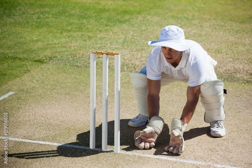 High angle view of wicketkeeper crouching behind stumps
