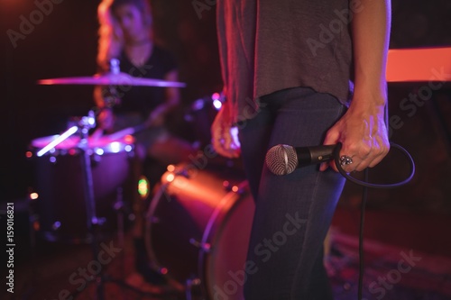 Female singer holding microphone with drummer 