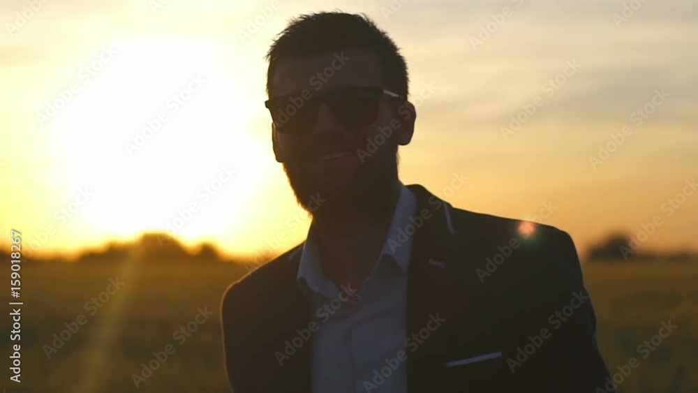 Businessman with beard show positive emotions in the field at sunset slow motion Businessman with beard show positive emotions in the field at sunset slow motion