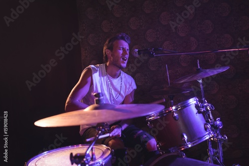 Singer playing drums while performing in nightclub
