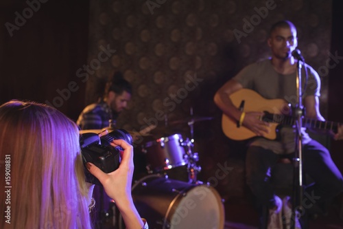 Woman photographing singer and musicians in nightclub