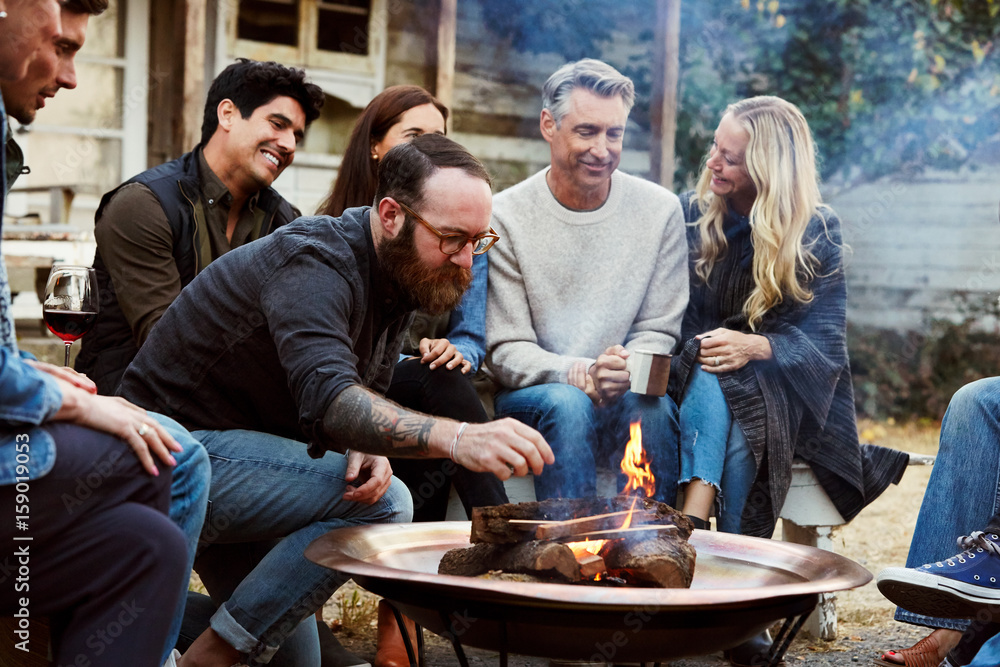 Group of friends and family relaxing around a fire pit at a farm Group of friends and family relaxing around a fire pit at a farm