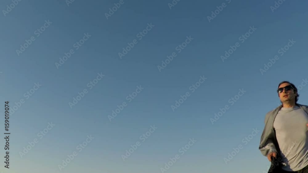 Man with briefcase and coffee runs against the sky Man with briefcase and coffee runs against the sky