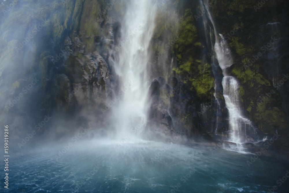 A large waterfall pours into the basin of Milford Sound, New Zealand A large waterfall pours into the basin of Milford Sound, New Zealand
