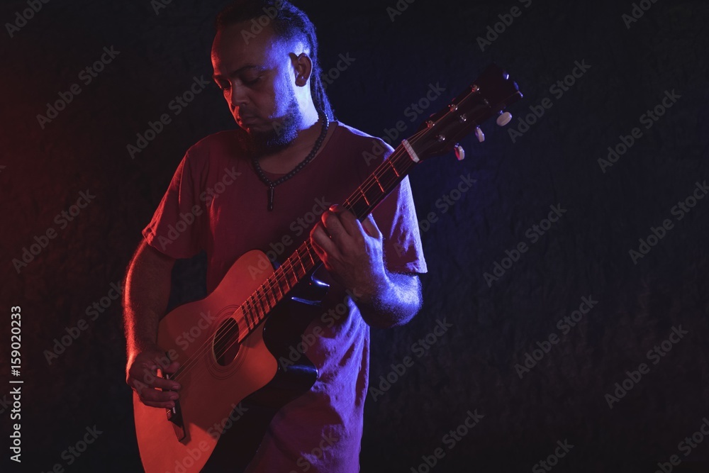 Obraz premium Male guitarist playing guitar at music concert