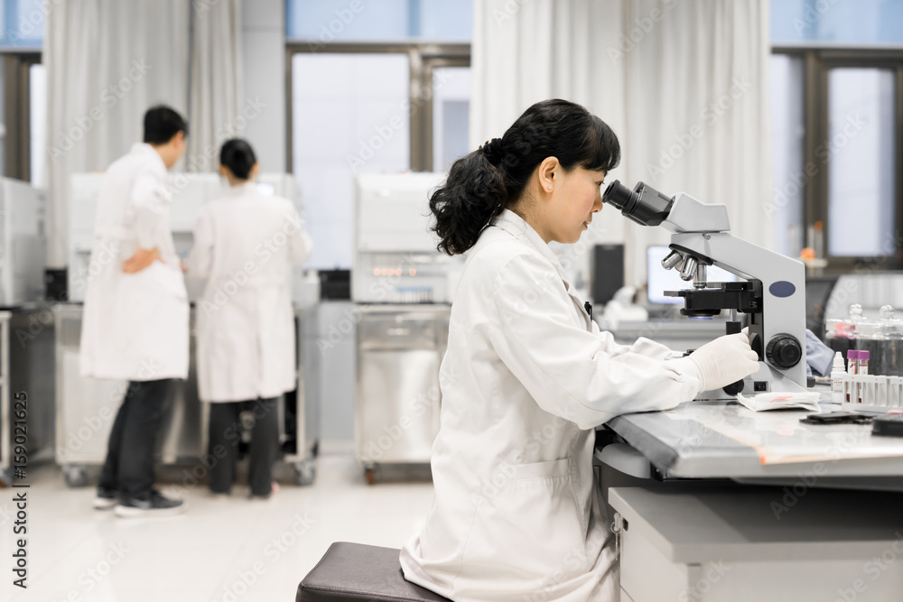 Female doctor looking into microscope Female doctor looking into microscope