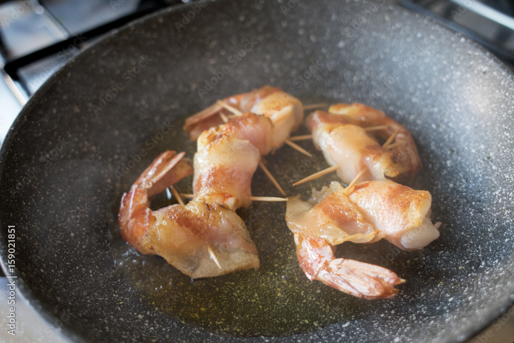 bacon wrapped shrimps frying in pan bacon wrapped shrimps frying in pan