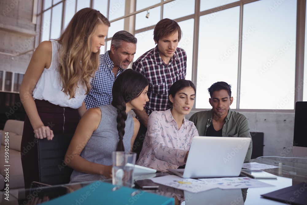 Business colleagues discussing over laptop at office