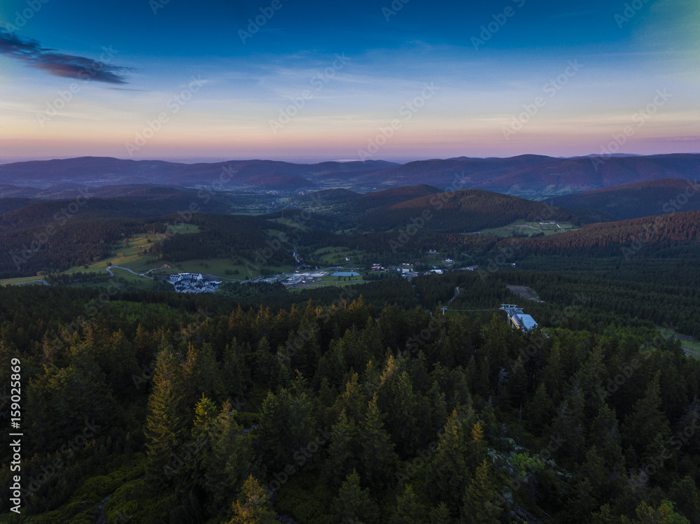 Sunset. Aerial view of the summer time in mountains near Czarna Gora mountain in Poland. Pine tree forest and clouds over blue sky. View from above.
