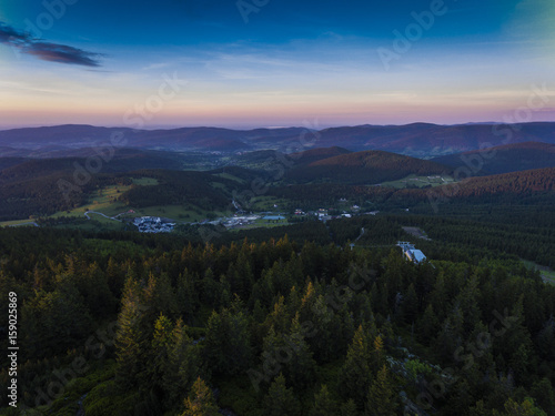 Sunset. Aerial view of the summer time in mountains near Czarna Gora mountain in Poland. Pine tree forest and clouds over blue sky. View from above.