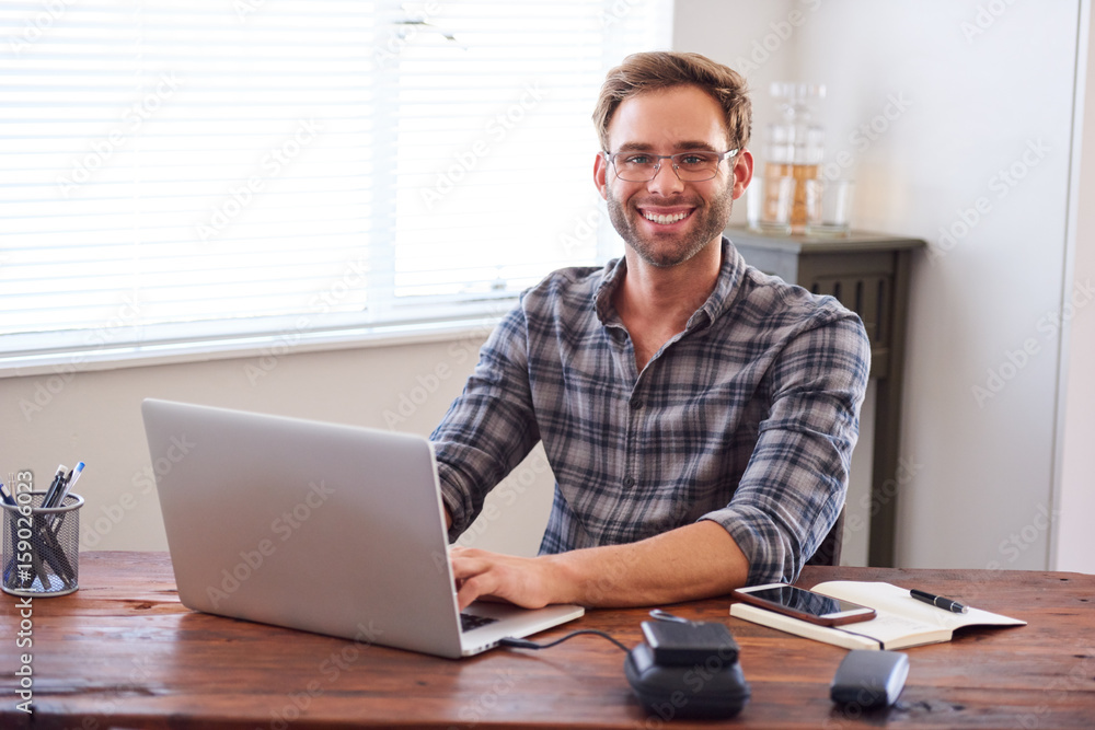 Attractive young, well groomed caucasian male entrepreneur and businessman smiling at the camera with his hands on the keyboard of his laptop computer. Attractive young, well groomed caucasian male entrepreneur and businessman smiling at the camera with his hands on the keyboard of his laptop computer.