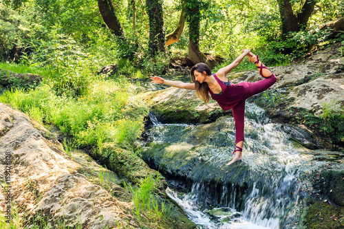 Jolie jeune femme sportive pratiquant le yoga dans la nature: posture du danseur - Natarajasana
