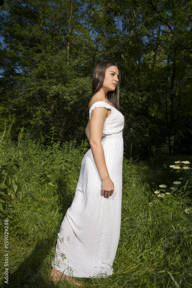Young girl with white dress posing in a grass field Young girl with white dress posing in a grass field