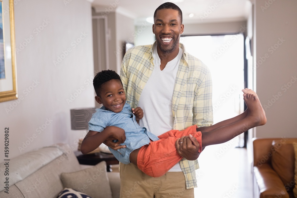 Obraz premium Playful father carrying son in living room