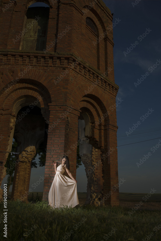Young girl posing near old water tower at sunset Young girl posing near old water tower at sunset