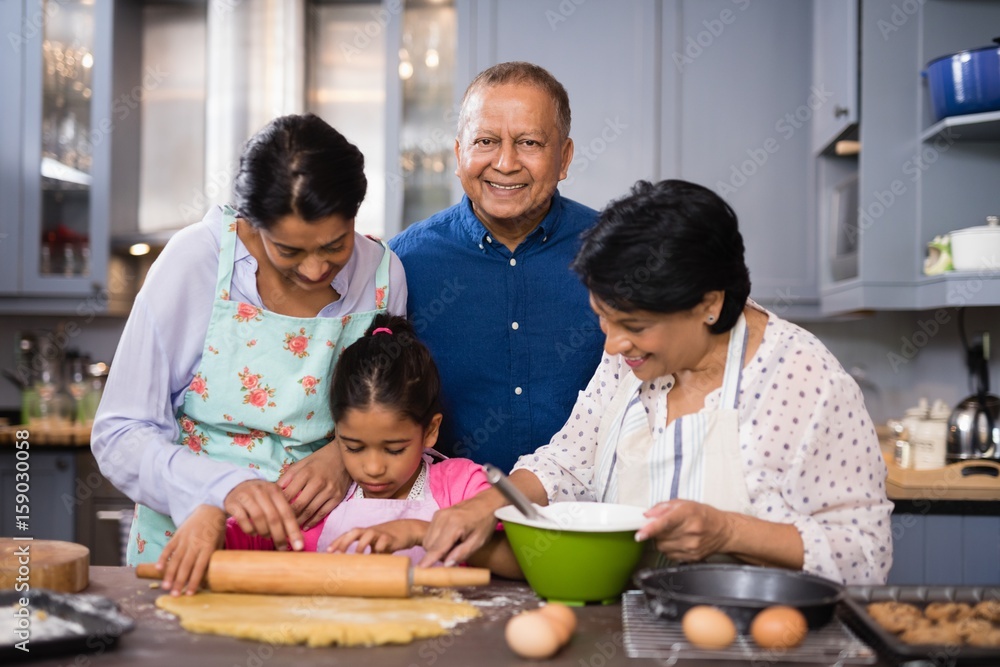Portrait of smiling man with family preparing food in kitchen Portrait of smiling man with family preparing food in kitchen