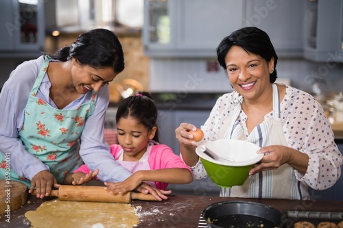 Portrait of woman preparing food with family in kitchen