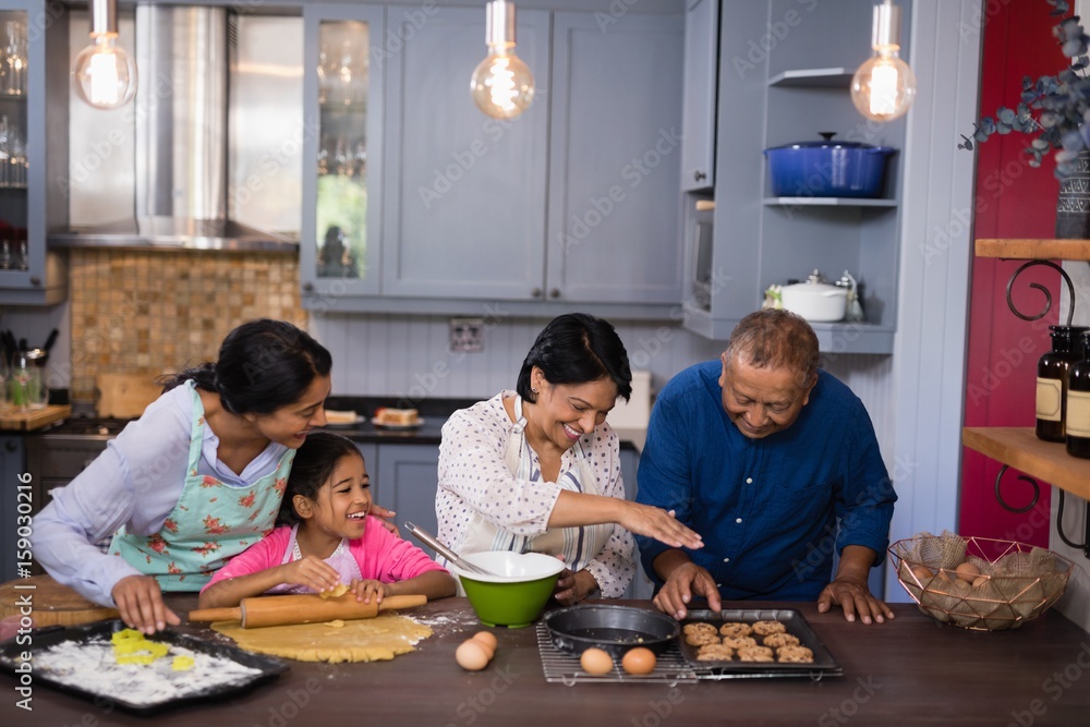 Happy multi-generation family preparing cookies in kitchen Happy multi-generation family preparing cookies in kitchen