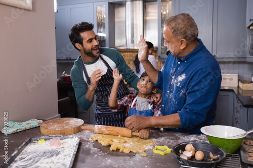 Happy multi-generation giving high five in kitchen