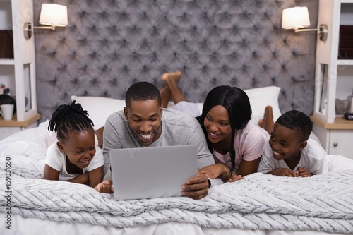 Smiling family using laptop while lying together on bed © wavebreak3