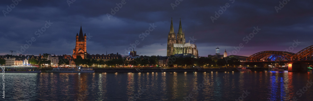 Night panorama of Cologne, Germany, with Cologne Cathedral, Great St. Martin Church, Colonius TV Tower and main train station reflecting in Rhine river
