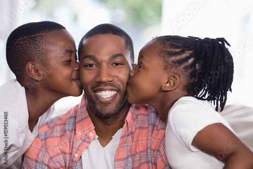Children kissing smiling father at home