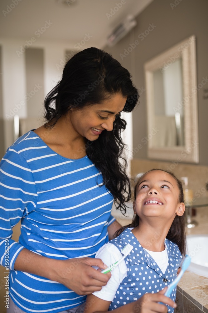 Girl with mother holding toothbrushes in bathroom Girl with mother holding toothbrushes in bathroom