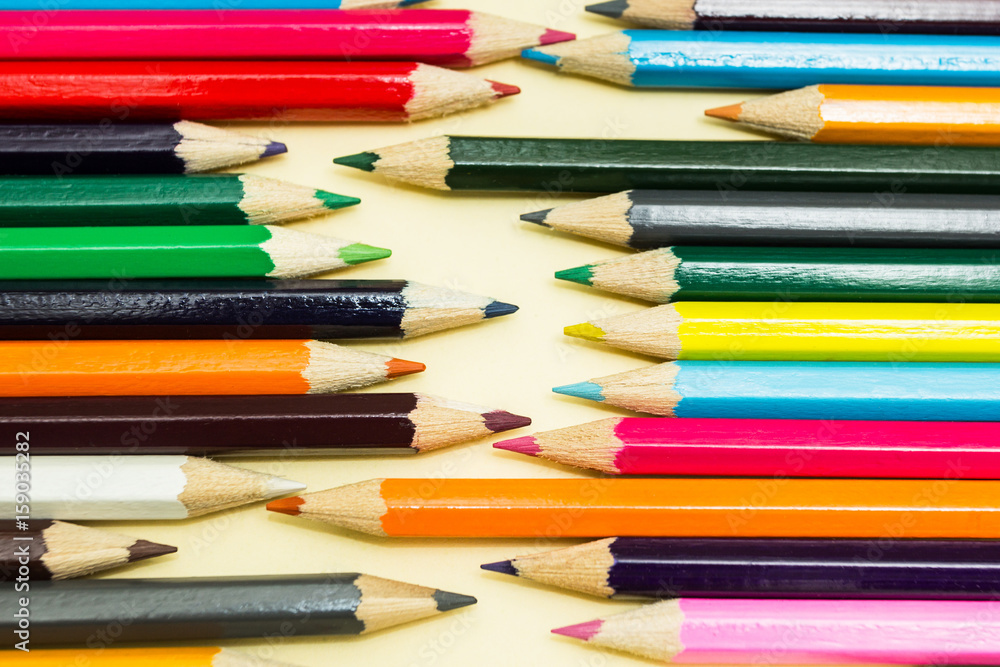 Multicolored pencils on a pastel yellow background Multicolored pencils on a pastel yellow background