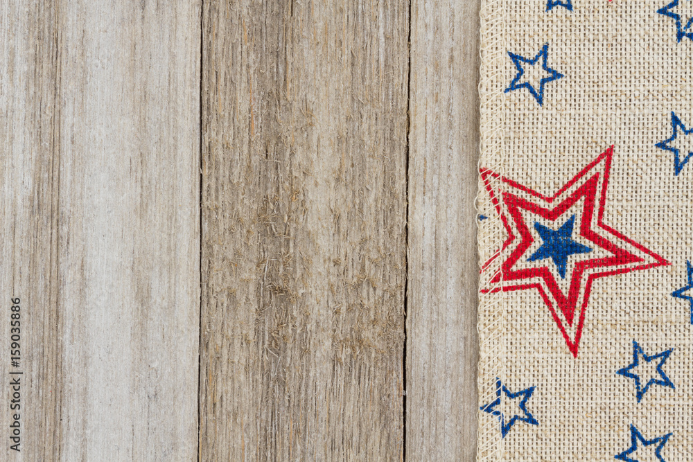 Obraz premium USA red and blue stars burlap ribbon on weathered wood background
