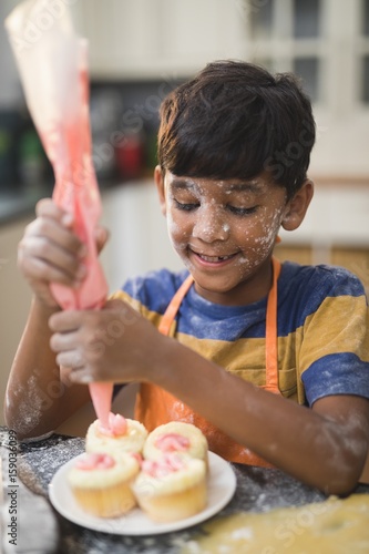 Boy making cup cakes in kitchen photo