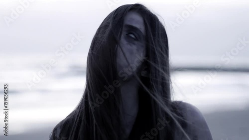 Zombie walking at dawn on beach hungry closeup slow motion