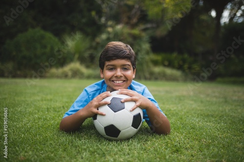 Portrait of smiling boy with soccer ball lying at park © WavebreakMediaMicro