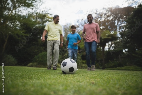 Multi-generation family playing soccer together at park