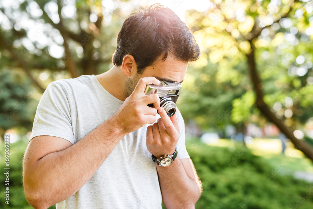 Handsome man in park taking photos with analog camera Handsome man in park taking photos with analog camera