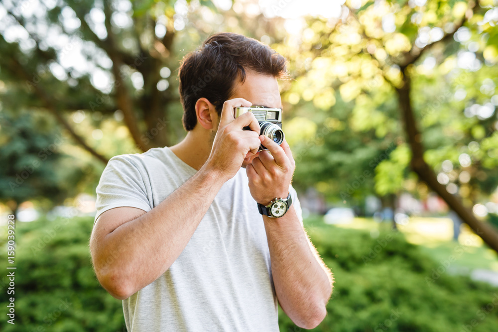 Handsome man in park taking photos with analog camera Handsome man in park taking photos with analog camera