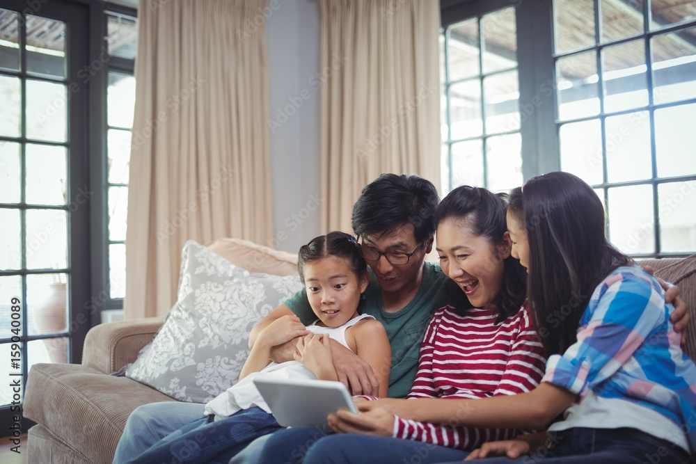 Smiling family using digital tablet together in living room Smiling family using digital tablet together in living room