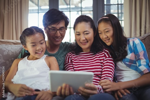 Smiling family using digital tablet together in living room