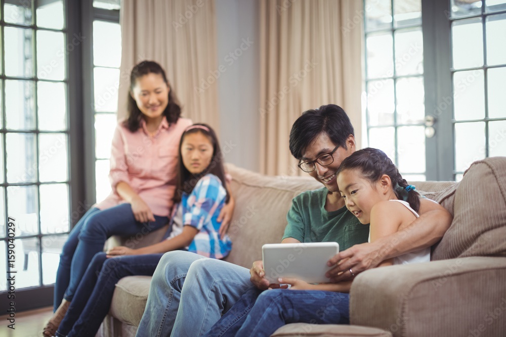 Smiling family using digital tablet together in living room Smiling family using digital tablet together in living room